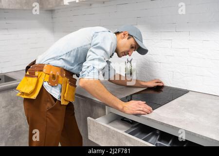 Installazione di fornelli a induzione piano di cottura o da parte di un maestro. Foto Stock