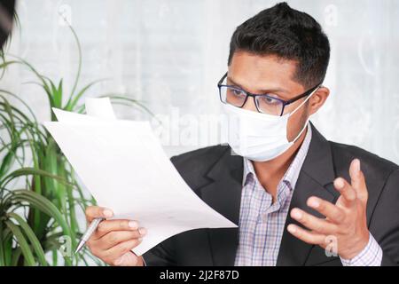 giovane uomo con maschera che legge qualcosa su un foglio Foto Stock