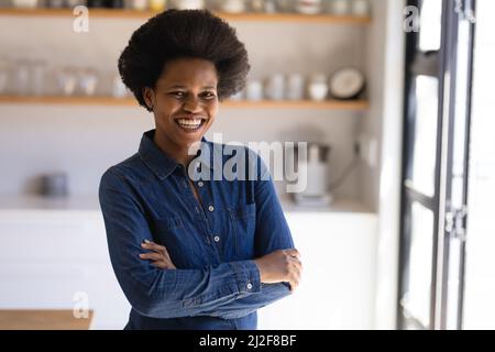 Ritratto di fiducioso medio adulto africano americano donna freelance con le braccia incrociate a casa Foto Stock
