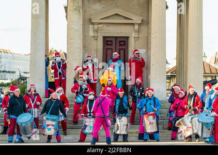 Gruppo di percussioni che si esibisce di fronte ai gradini di pietra e alle colonne della torre dell'orologio di Herne Bay in una fredda giornata invernale a Natale. Prospettiva compressa. Foto Stock