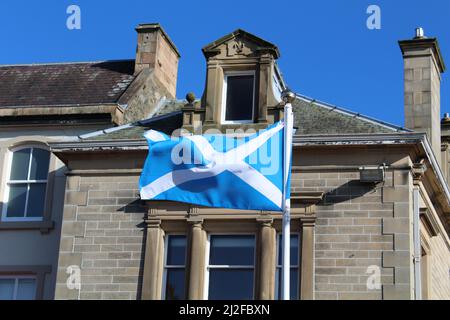 Bandiera della Scozia, conosciuta anche come St Andrew's Cross o il Saltyre, vola al vento in una giornata estiva soleggiata (High Street, Peebles, Scozia) Foto Stock