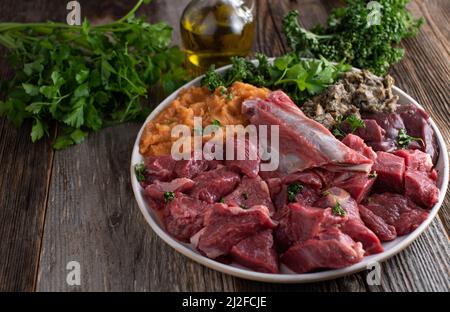 Cibo crudo per cani, carne biologica e fresca, rumine, frattaglie, verdure, erbe e olio. Pasto sano per animali domestici Foto Stock