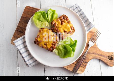 Tostare e fagioli con formaggio cheddar su un piatto Foto Stock
