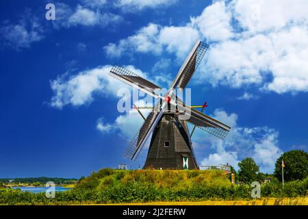 Beesel, Paesi Bassi - Juin 9. 2021: Vista su un tipico mulino a vento olandese in legno (birra Molen de grauwe) in paesaggio rurale contro il cielo blu estivo con Foto Stock