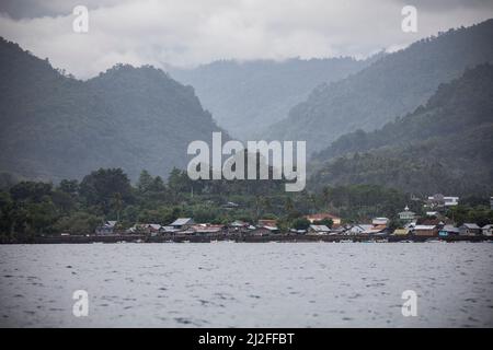 Le montagne incontrano la costa in un piccolo villaggio di pescatori vicino a Mamuju sull'isola di Sulawesi, nell'arcipelago indonesiano. Foto Stock