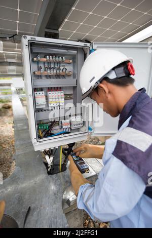 Un tecnico elettrico gestisce le apparecchiature in un impianto di energia solare sull'isola di Karampuang, Indonesia, Asia. Foto Stock