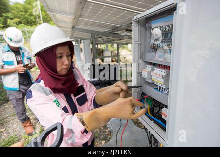 Tecnici maschili e femminili ispezionano e mantengono i pannelli solari sull'isola di Karampuang, Indonesia, Asia. Foto Stock