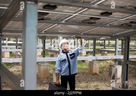 Un tecnico elettrico gestisce le apparecchiature in un impianto di energia solare sull'isola di Karampuang, Indonesia, Asia. Foto Stock