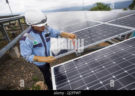 Un tecnico elettrico gestisce le apparecchiature in un impianto di energia solare sull'isola di Karampuang, Indonesia, Asia. Foto Stock