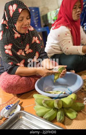 Una donna sbuccia un mucchio di banane verdi nella sua casa a Karampuang Island, Sulawesi occidentale, Indonesia, Asia. Foto Stock