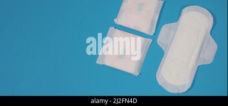 Assorbenti igienici donna su sfondo blu. Vista dall'alto. Tamponi assorbenti indossati dalle donne per assorbire il sangue mestruale. Comodi assorbenti igienici bianchi disposti Foto Stock