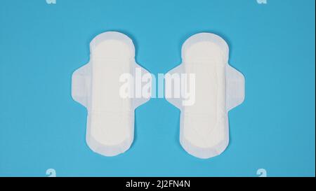 Assorbenti igienici donna su sfondo blu. Vista dall'alto. Tamponi assorbenti indossati dalle donne per assorbire il sangue mestruale. Comodi assorbenti igienici bianchi disposti Foto Stock