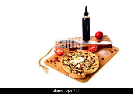 Pizza su un tagliere con un coltello per il pane. Pomodori, salsa, uova. Foto Stock