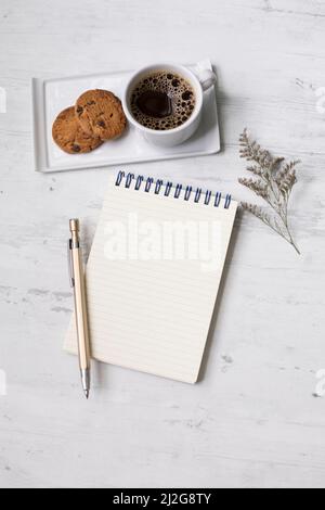 Piccolo blocco appunti e penna dorata con biscotti e caffè per prendere appunti elenco Foto Stock