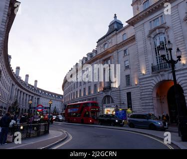 Londra, Grande Londra, Inghilterra, marzo 12 2022: Traffico in Regent Street in serata con la stazione della metropolitana di Piccadilly Circus in primo piano Foto Stock