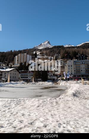 Davos, Svizzera, 23 marzo 2022 lago ghiacciato in un piccolo parco circondato da un fantastico panorama invernale alpino in una giornata di sole Foto Stock