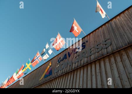 Davos, Svizzera, 23 marzo 2022 diverse bandiere nazionali sventolano sull'ingresso dell'edificio del centro congressi in una giornata di sole Foto Stock