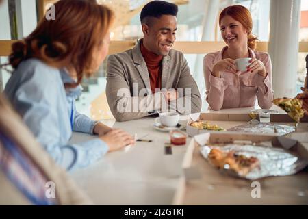 Un gruppo di giovani colleghi si sta godendo la pausa pranzo al lavoro in un'atmosfera rilassata. Affari, persone, mensa, azienda Foto Stock