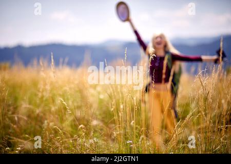 Scatto sfocato di una giovane donna escursionista che gode della natura a braccia aperte. Spensierato, soleggiato, libero, felice. Sport, libertà, concetto di vacanza. Foto Stock