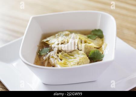 Un primo piano di una ciotola di gnocchi cinesi (jiaozi) in un brodo Foto Stock