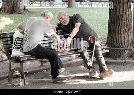 SOFIA, BULGARIA - 02 AGOSTO 2017: Due uomini di mezza età seduti su una panchina e giocando una partita di scacchi in un giardino della città di Sofia centro Foto Stock