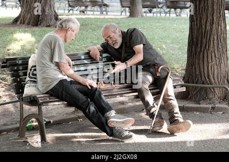 SOFIA, BULGARIA - 02 AGOSTO 2017: Due uomini di mezza età seduti su una panchina e giocando una partita di scacchi in un giardino della città di Sofia centro Foto Stock