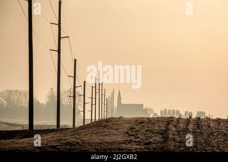 Pali telefonici e campanile di una chiesa accanto a un campo nel Midwest rurale americano Foto Stock