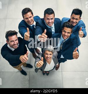 Noi tutti approviamo. Ritratto di un gruppo di uomini d'affari che mostrano i pollici insieme in un ufficio. Foto Stock