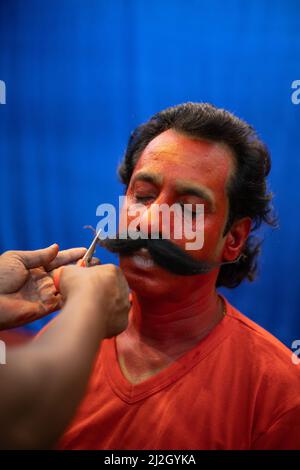 L'artista di makeover che collega i baffi finti al volto dell'uomo dovrebbe giocare il ruolo di Virabhadra per la performance di danza folk annuale a Goa Foto Stock