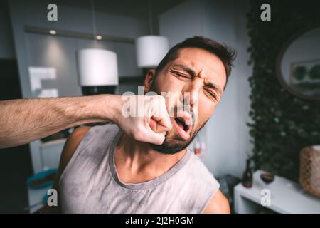 L'uomo prende il pugno duro in faccia. Due uomini che combattono. Uomo che colpisce l'uomo in faccia con pugno. Conflitto e violenza Foto Stock