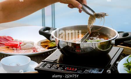 Man mano prendere il gambero di fiume e metterlo in pentola bollente Shabu shabu stile hotpot Foto Stock