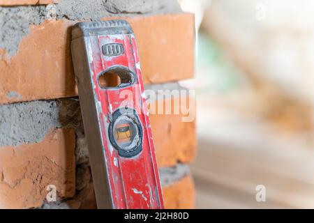 Livello di costruzione di colore rosso in un cantiere stantio su un muro di mattoni Foto Stock