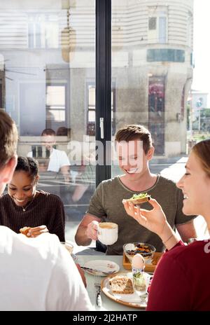 Amici sorridenti che gustano la colazione al ristorante Foto Stock