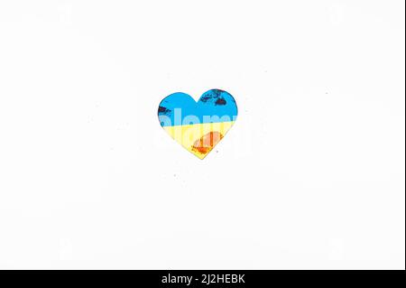 Il cuore con la bandiera dell'Ucraina è cosparso di sangue su sfondo bianco. Foto Stock