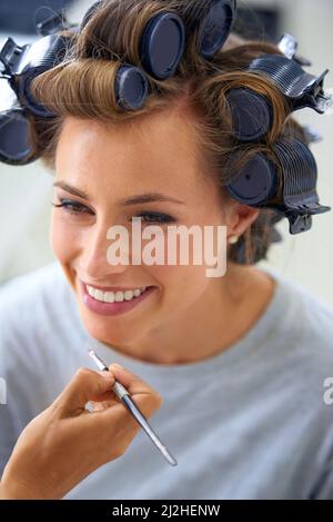 Curly e spensierato. Una bella giovane donna che passa la giornata ottenendo i suoi capelli e trucco fatto. Foto Stock