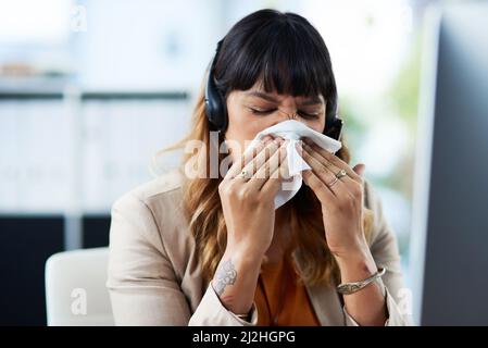 OH OH, penso di avere un freddo. Scatto corto di una giovane donna d'affari attraente che soffre di un freddo e soffia il suo naso mentre nel suo ufficio. Foto Stock