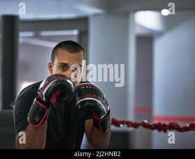 Lavorando sulla sua forma. Ritratto corto di un giovane atleta maschile che si allenano all'interno di un anello di pugilato. Foto Stock