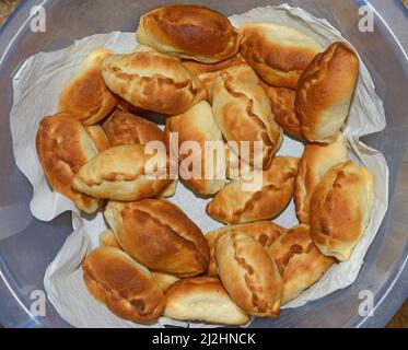 Molti russi tradizionali polpette al forno su carta nel profondo blu coppa in plastica. Foto Stock