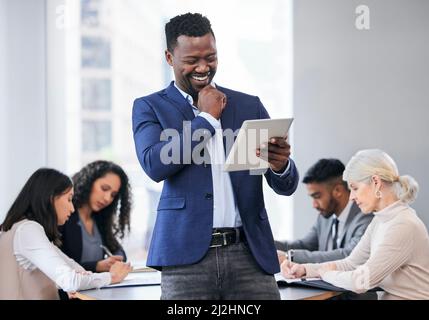 Ive arrivare fino ad ora. Scatto di un giovane uomo d'affari che usa un tablet digitale durante una riunione di affari. Foto Stock