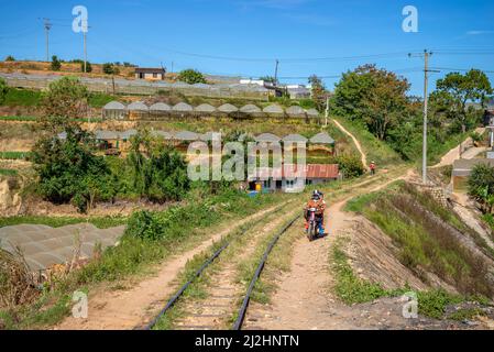 DALAT, VIETNAM - 27 DICEMBRE 2015: Paesaggio rurale con serre e una ferrovia abbandonata. Dintorni di Dalat, Vietnam Foto Stock