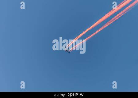 Aeroplano in un cielo blu senza nuvole con contraglie colorate senza nuvole durante il tramonto e l'ora d'oro, Germania Foto Stock