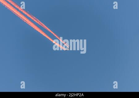 Aeroplano in un cielo blu senza nuvole con contraglie colorate senza nuvole durante il tramonto e l'ora d'oro, Germania Foto Stock
