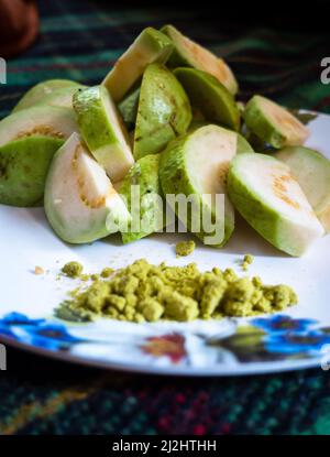 Un primo colpo di insalata di guava servito con sale verde di spezie miste indiane su un piatto bianco. Foto Stock