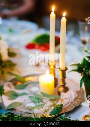 Piante verdi e candele su tavolo servito primo piano Foto Stock
