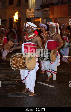 I giocatori di Davul si esibiscono lungo una strada durante l'Esala Perahera buddista (grande processione) a Kandy in Sri Lanka. Foto Stock