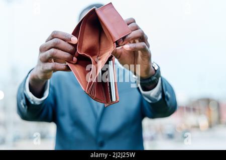 Fuoco selettivo di un uomo di borsa vuoto e di un uomo afroamericano con vestito e legare in background fuori-di-fuoco Foto Stock