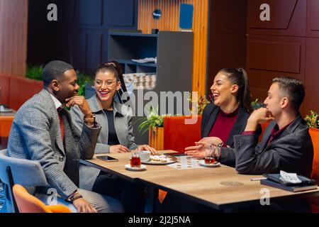 Gruppo di uomini di affari multirazziali stanno ridendo e parlando al bar Foto Stock