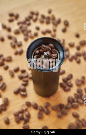 Macinacaffè manuale per macinare chicchi di caffè con chicchi di caffè e caffè macinato su sfondo di legno Foto Stock