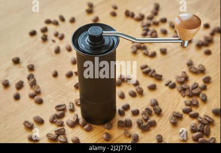 Macinacaffè manuale per macinare chicchi di caffè con chicchi di caffè e caffè macinato su sfondo di legno Foto Stock