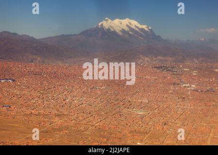 Una vista aerea della montagna rocciosa e nevosa di Illimani sotto il cielo blu in Bolivia Foto Stock